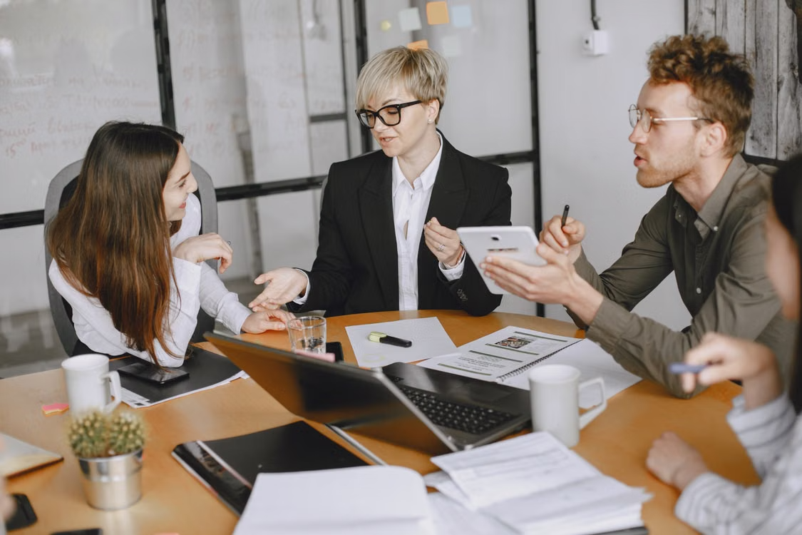Three advisers reviewing calibration documents across a meeting table